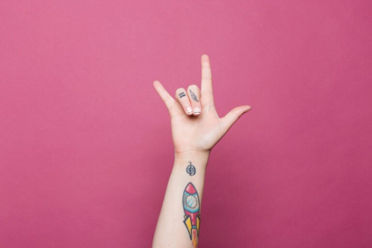 Main réalisant un signe en langue des signes sur fond rose