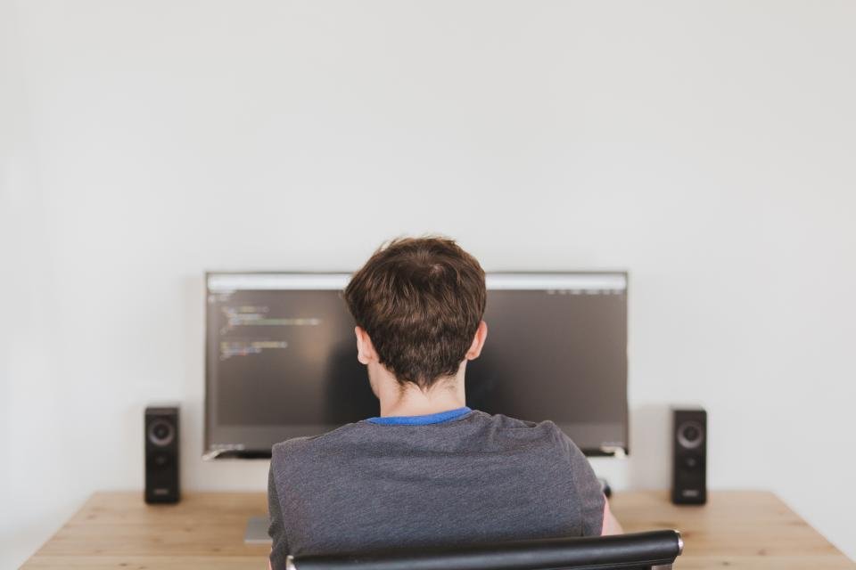 Personne de dos face à un grand écran affichant du code